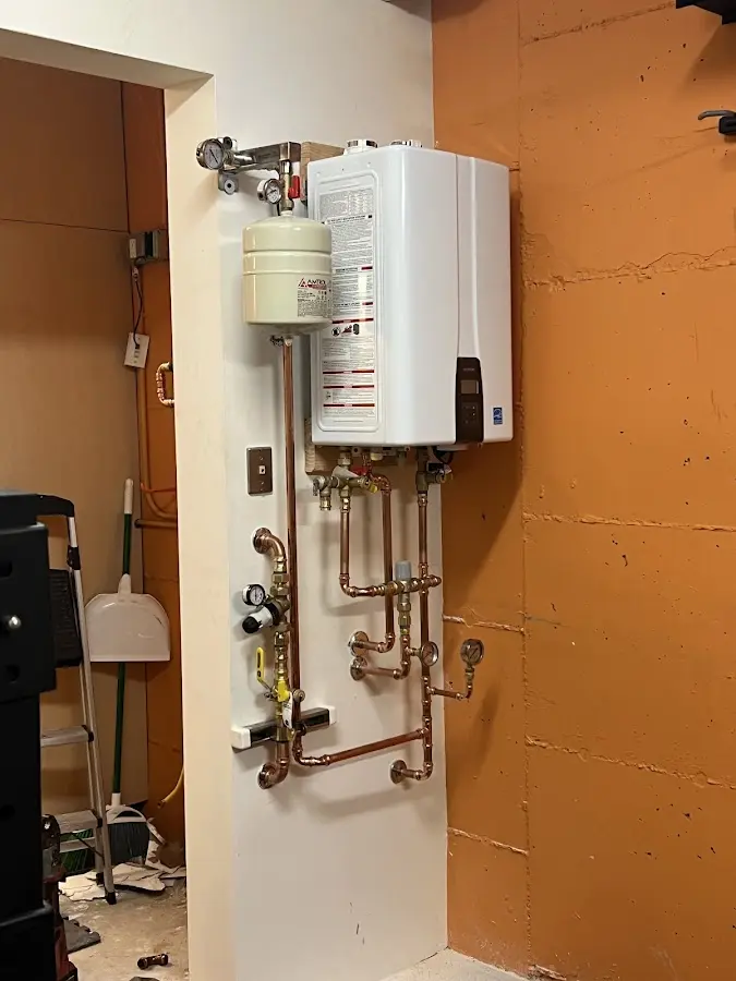 Plumbing technician inspecting water heater connections in Tupper Lake